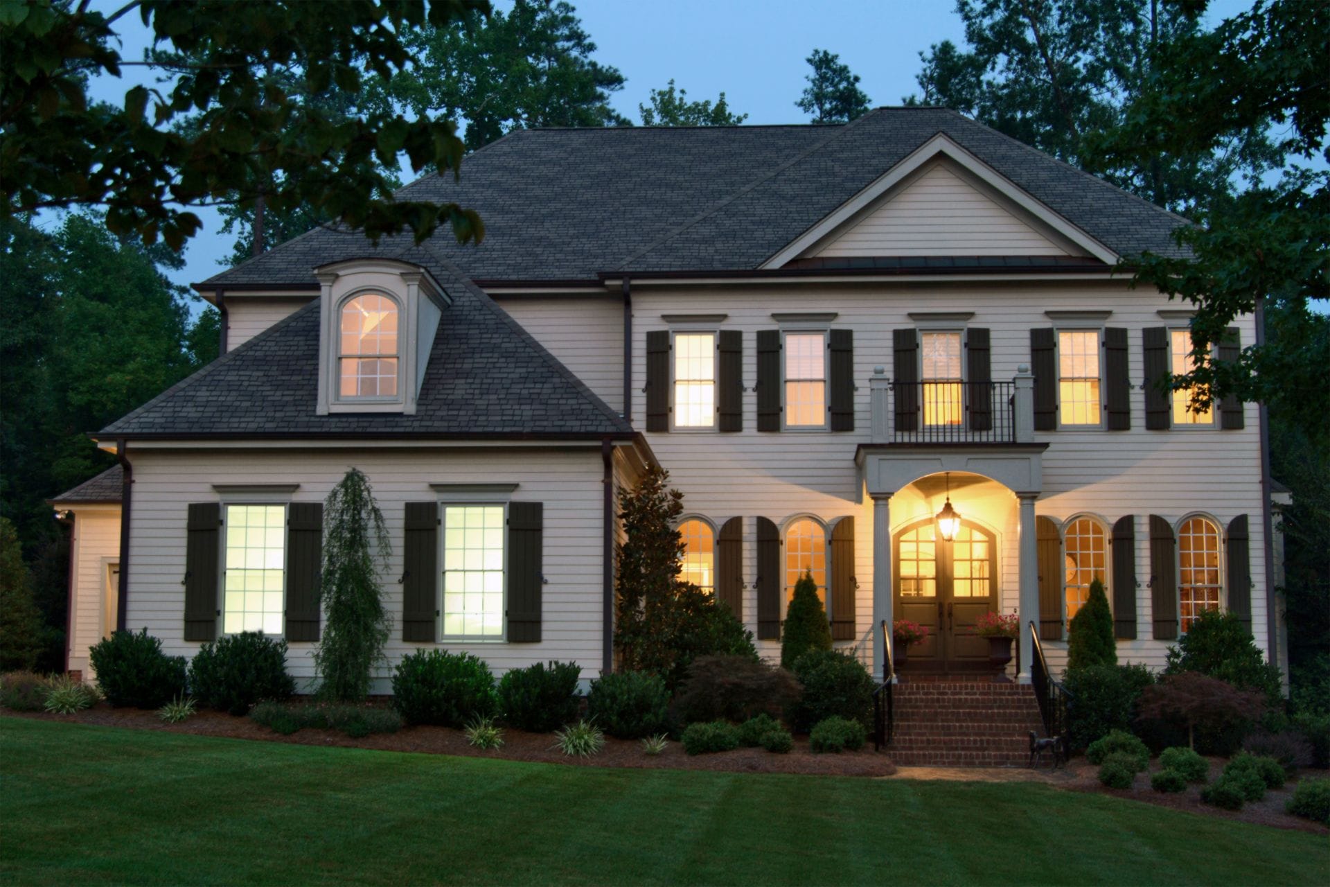 A residential home with a large front porch painted at dusk.